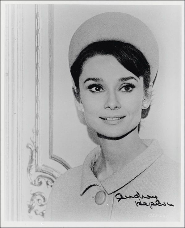 Lot 1061 Audrey Hepburn: ?Sounds like....?: HEPBURN signs a photo from Charade